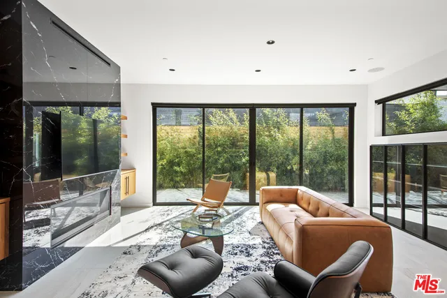 a living room with furniture large windows and wooden floor