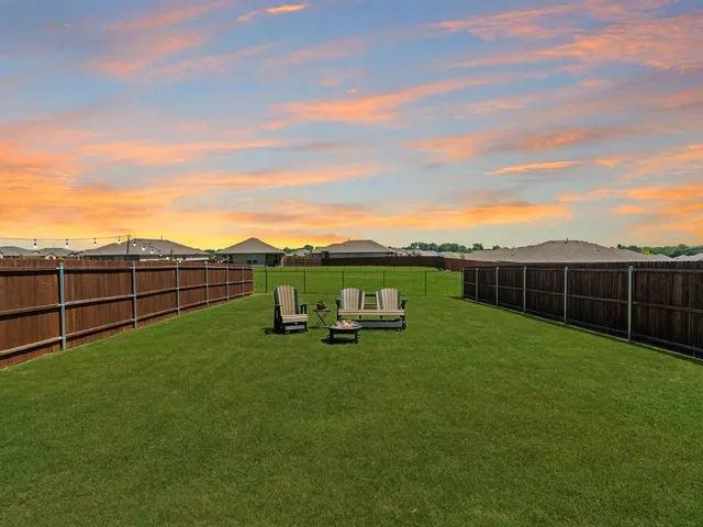 a view of a backyard with lawn chairs wooden floor and fence