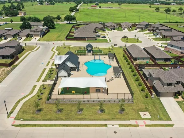 a view of a swimming pool with a yard and large trees