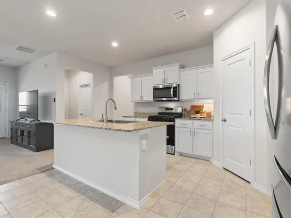 a kitchen with kitchen island granite countertop a refrigerator stove top oven and sink