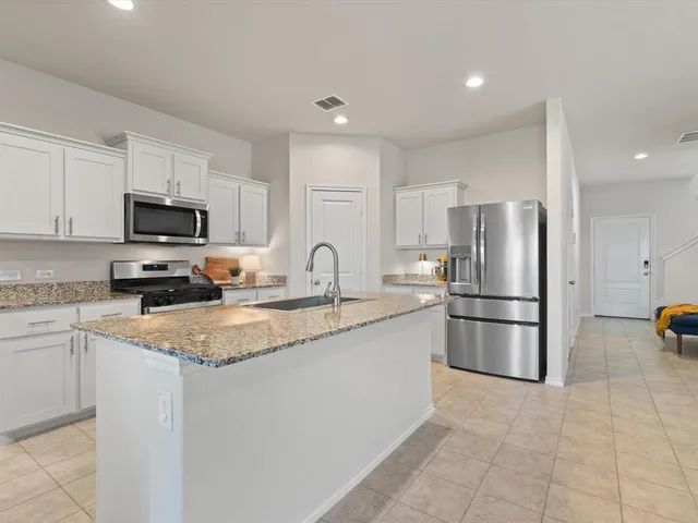 a kitchen with a refrigerator a microwave a sink and cabinets