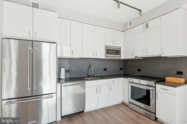 a kitchen with white cabinets and stainless steel appliances