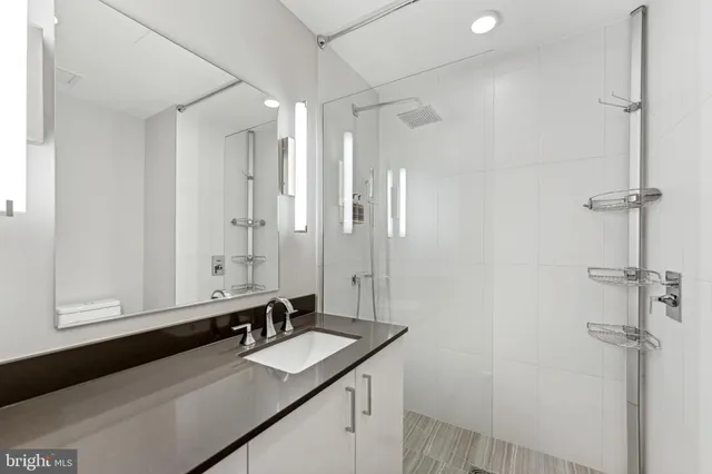 a bathroom with a granite countertop sink mirror and a shower