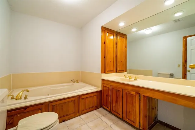 a bathroom with a granite countertop sink mirror bathtub and toilet