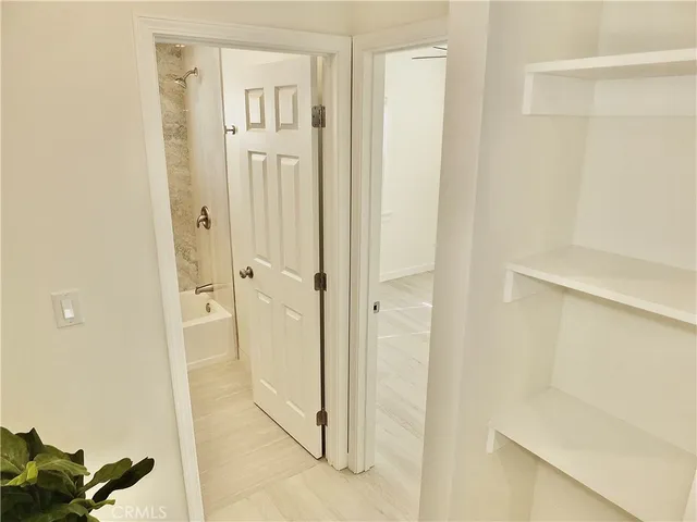 a view of a hallway with wooden floor and closet area