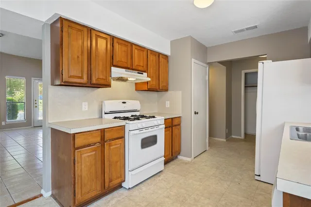 a kitchen with stainless steel appliances granite countertop a stove a sink and a refrigerator with wooden cabinets