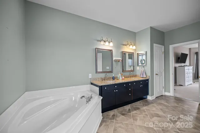 a large bathroom with a granite countertop sink a mirror and a bathtub