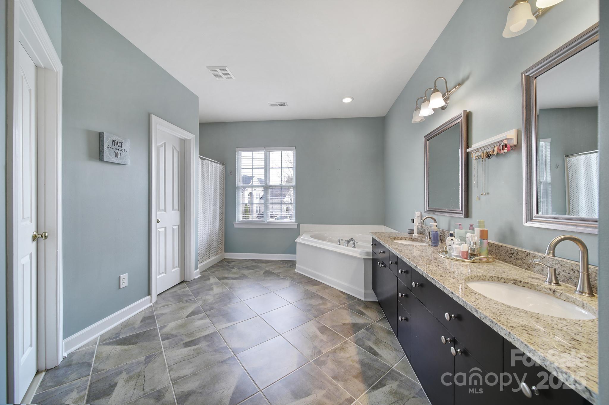 1002 Dataw Lane Indian Trail, NC 28079 - Photo 28 of 36 a large bathroom with a granite countertop sink a mirror and a bathtub