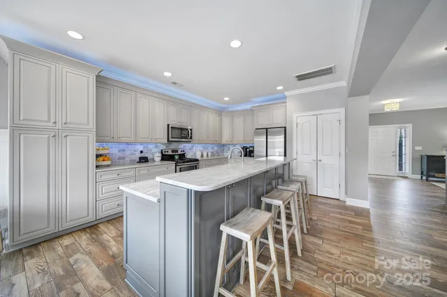 a kitchen with white cabinets and a stove with wooden floor
