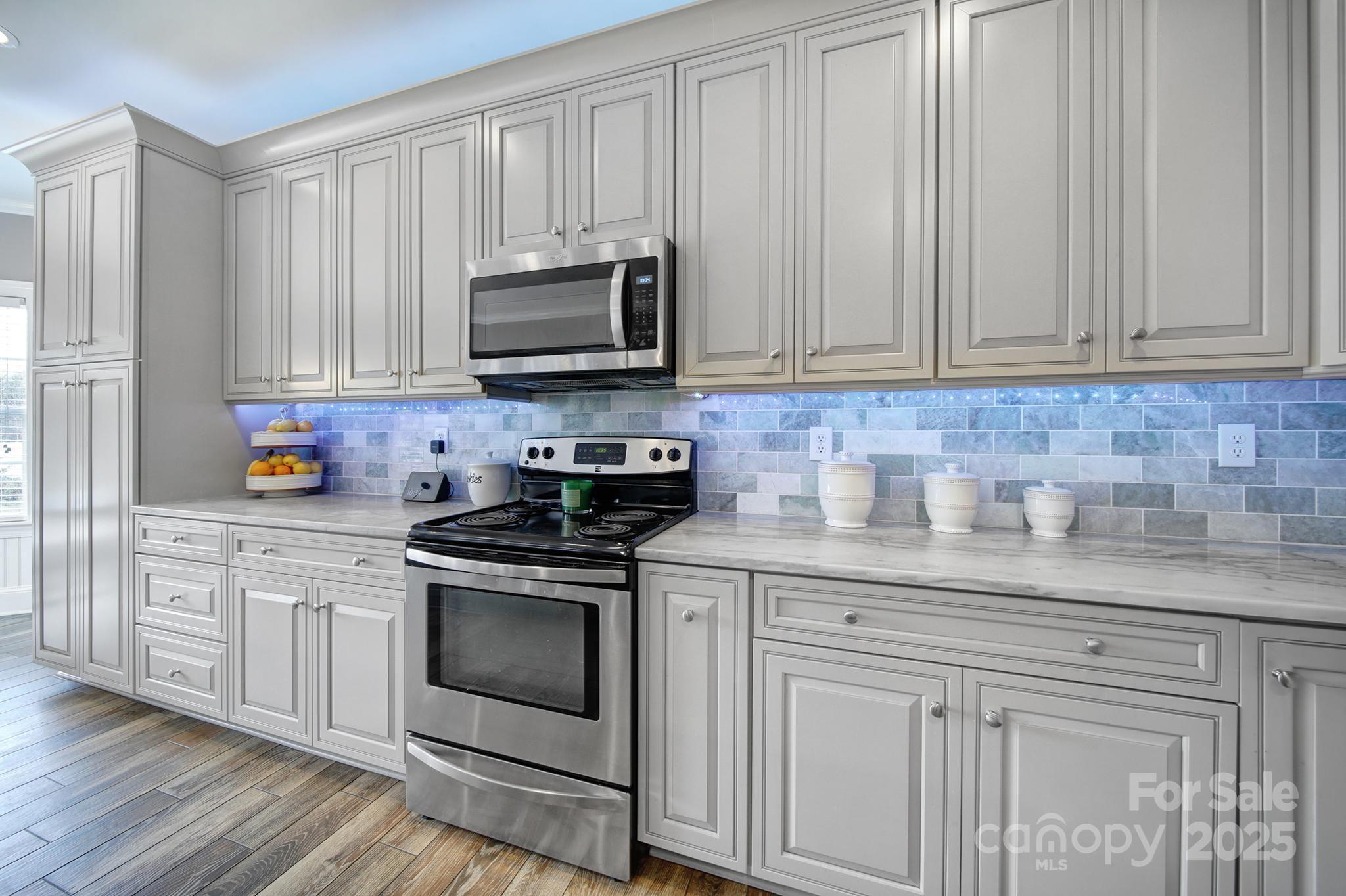 1002 Dataw Lane Indian Trail, NC 28079 - Photo 7 of 36 a kitchen with white cabinets and a stove with wooden floor