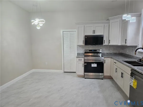 a kitchen with granite countertop a stove a sink and a microwave