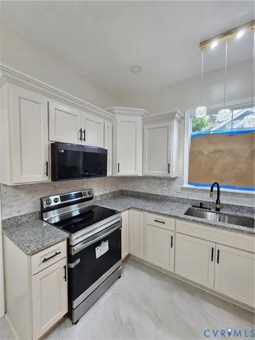 a kitchen with granite countertop a sink a stove and cabinets