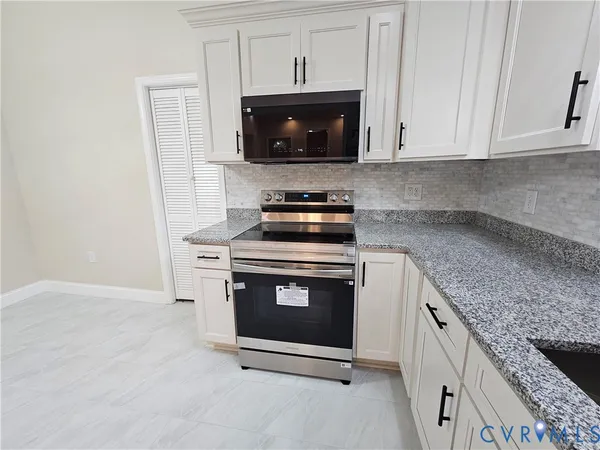 a kitchen with granite countertop white cabinets and stainless steel appliances