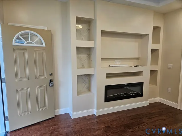 a view of a livingroom with a fireplace wooden floor and windows