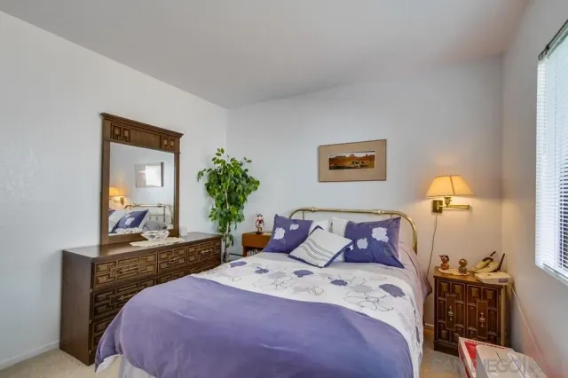 a bedroom with a bed and a potted plant on dresser
