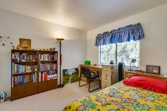a bedroom with a bed a large window and a book shelf