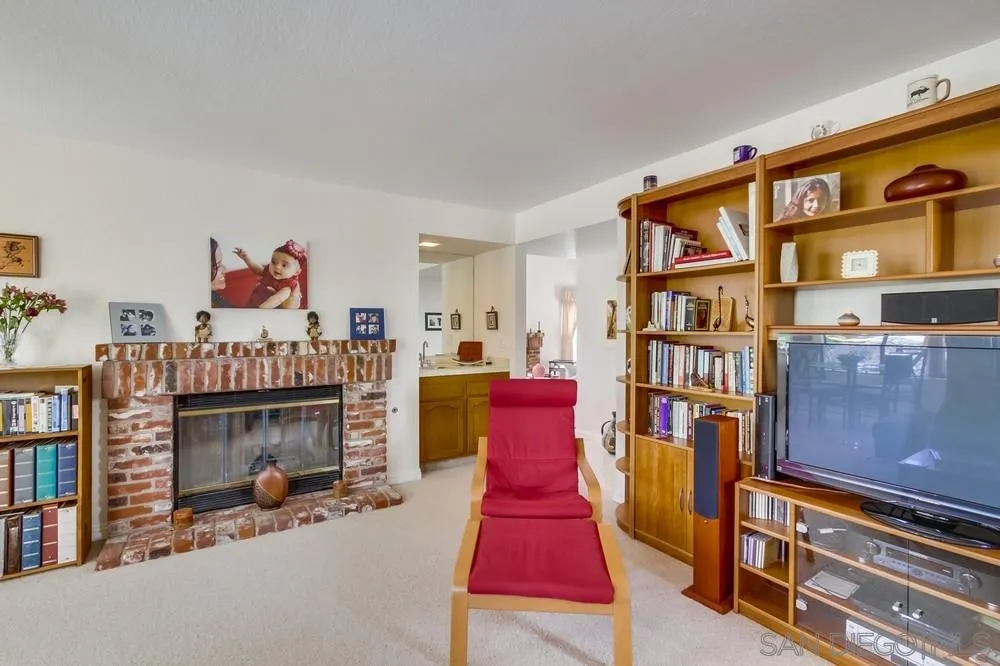 13354 Benchley Road San Diego, CA 92130 - Photo 6 of 24 a living room with furniture a fireplace and a book shelf