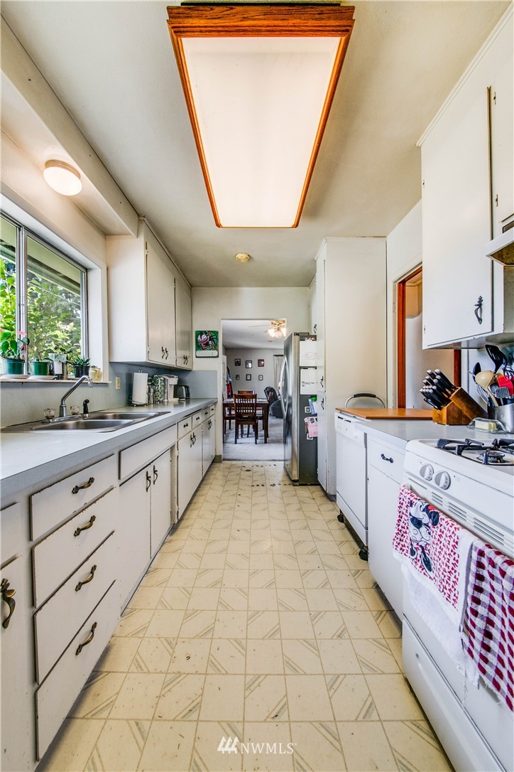 902 South Mullen Street Tacoma, WA 98405 - Photo 15 of 30 a large white kitchen with stainless steel appliances granite countertop a large stove a sink dishwasher and cabinets next to a window