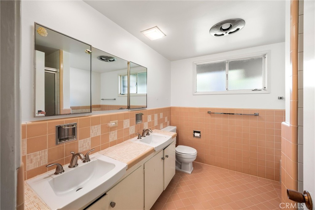 8780 Hillcrest Road Buena Park, CA 90621 - Photo 43 of 62 a bathroom with a double vanity sink a toilet and a mirror