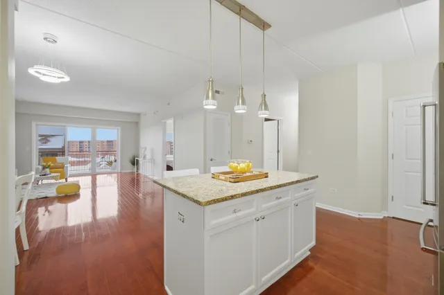 a hall with kitchen island a sink dishwasher a stove and a dining table with wooden floor