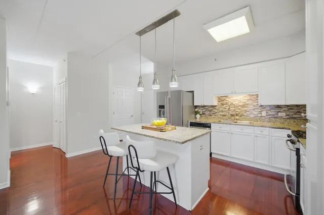 a kitchen with stainless steel appliances kitchen island granite countertop a table chairs and a refrigerator