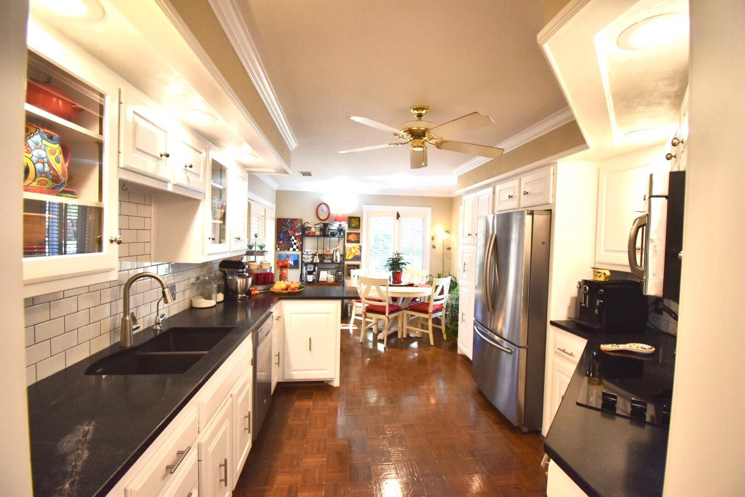 8201 Durham Avenue Lubbock, TX 79424 - Photo 13 of 33 a kitchen with stainless steel appliances granite countertop a refrigerator a sink dishwasher a stove and a dining table with wooden floor