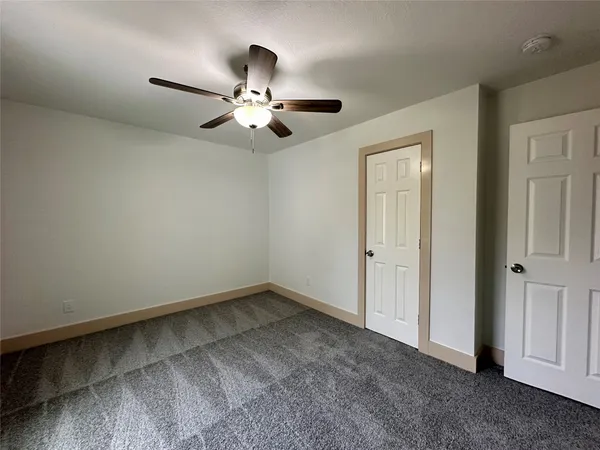 an empty room with a window and a fan