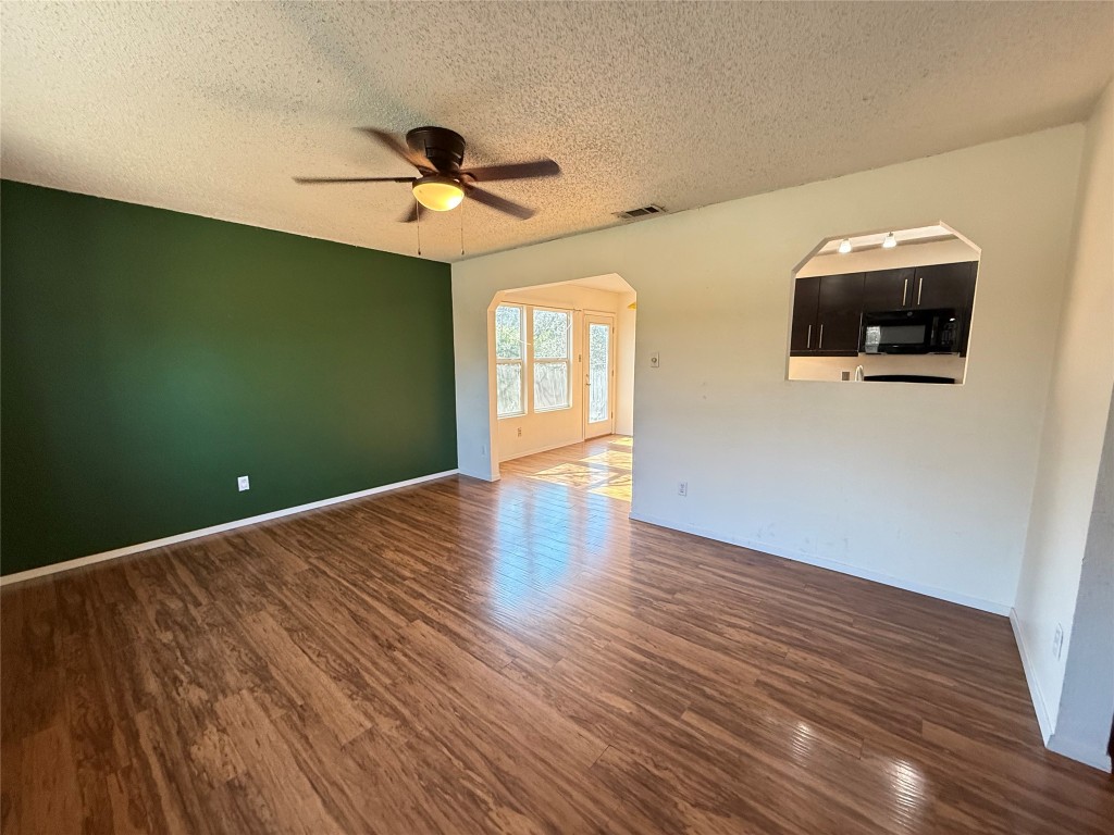 6200 Boxcar Run Austin, TX 78745 - Photo 3 of 7 Unfurnished room with arched walkways, dark wood-style floors, a textured ceiling, and a ceiling fan