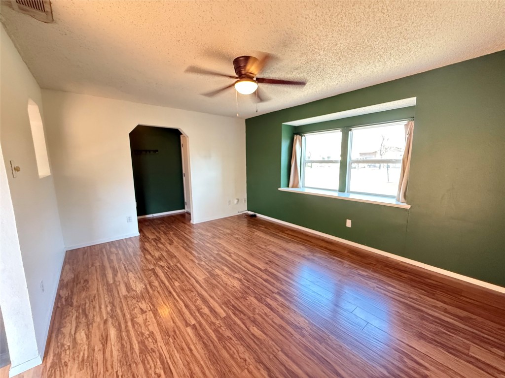 6200 Boxcar Run Austin, TX 78745 - Photo 4 of 7 Empty room with arched walkways, a textured ceiling, a ceiling fan, and wood finished floors