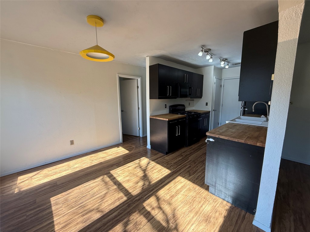 6200 Boxcar Run Austin, TX 78745 - Photo 5 of 7 Kitchen with dark cabinets, pendant lighting, black appliances, dark wood-type flooring, and wood counters