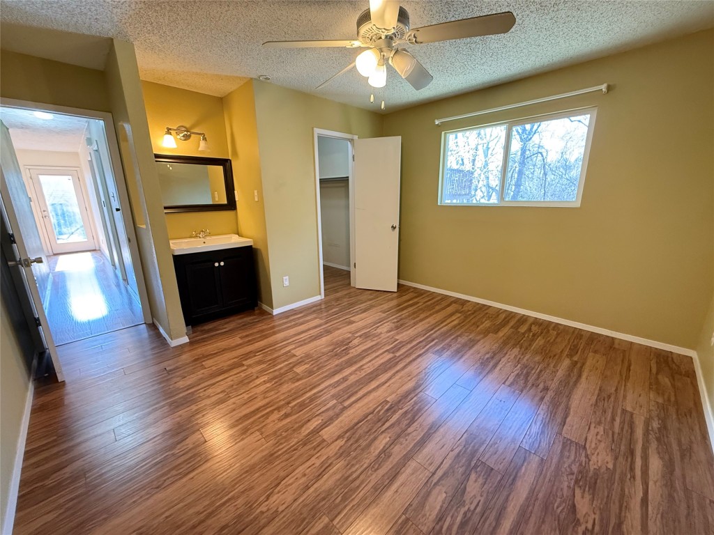 6200 Boxcar Run Austin, TX 78745 - Photo 7 of 7 Unfurnished bedroom with a walk in closet, dark wood-style flooring, ensuite bathroom, ceiling fan, and a textured ceiling