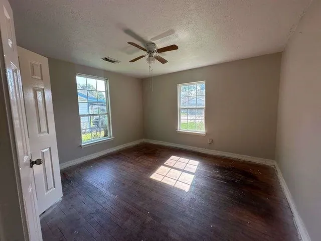 a view of an empty room with wooden floor and a window