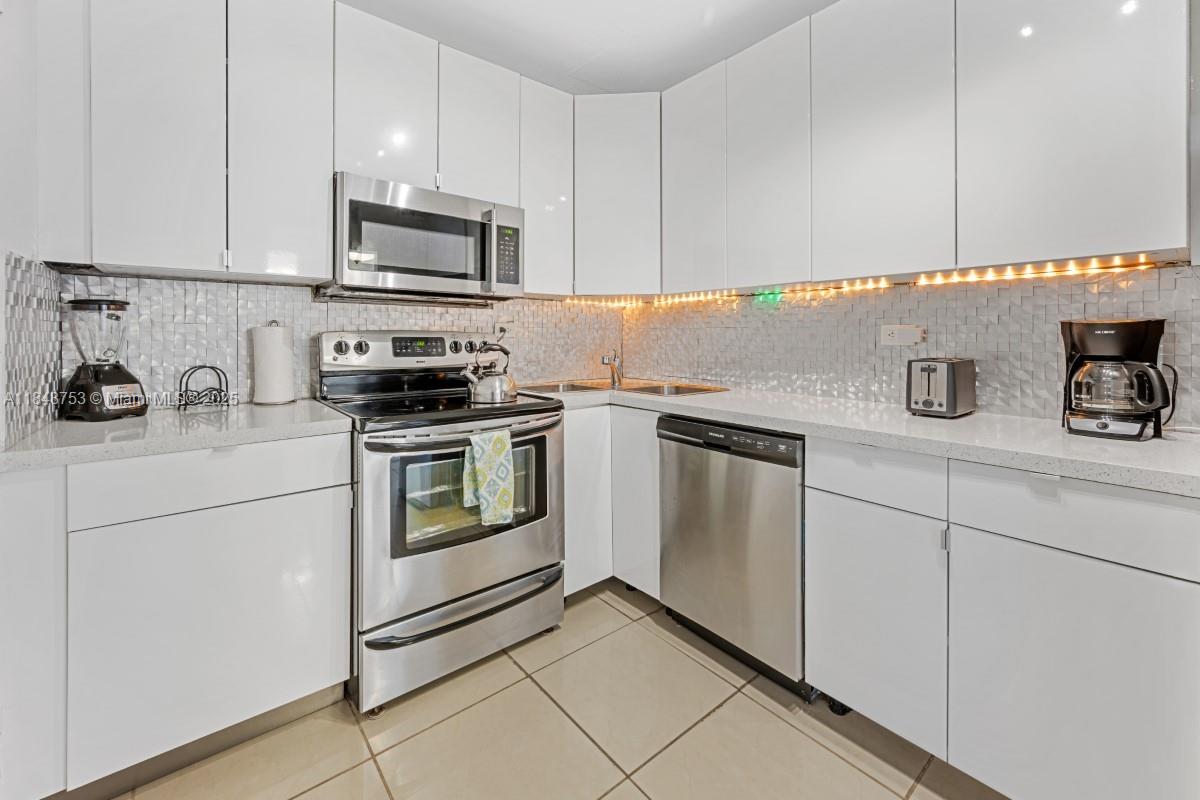 5601 Collins Avenue, Unit 511 Miami Beach, FL 33140 - Photo 16 of 34 a kitchen with white cabinets and white appliances