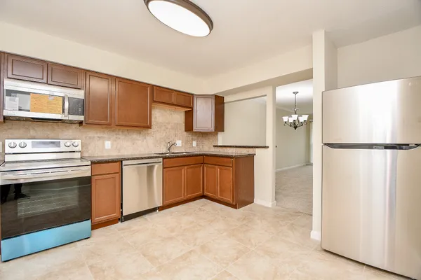 a kitchen with stainless steel appliances granite countertop a refrigerator a stove a sink and a microwave