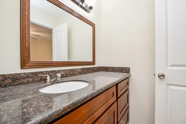 a bathroom with a granite countertop sink and a mirror
