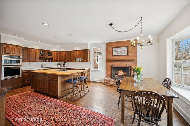 a large hall with stainless steel appliances granite countertop a stove and a dining table with wooden floor