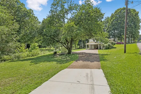 a view of a house with a big yard and large trees