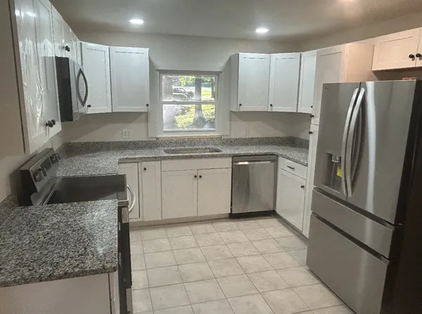 a kitchen with stainless steel appliances granite countertop a sink stove and refrigerator
