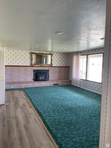 438 East Main Street Elsinore, UT 84724 - Photo 14 of 43 Spacious room featuring a brick fireplace with a dark insert, large windows, recessed lighting, wood-finish flooring, and wall-to-wall carpeting