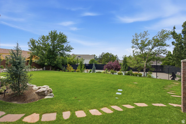 12308 Mariah Circle Draper, UT 84020 - Photo 238 of 293 Guest House Expansive backyard featuring a lush lawn, mature trees, natural rock landscaping, stepping stone path, and a partially visible sports court