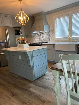 a kitchen with stainless steel appliances granite countertop wooden floors wooden cabinets and window