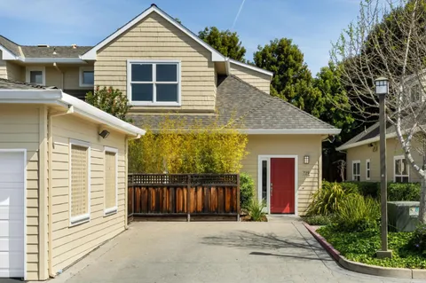 a view of a house with a small yard plants and a large tree