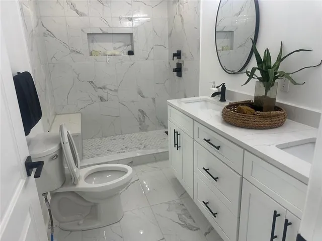 a bathroom with a granite countertop toilet sink and mirror