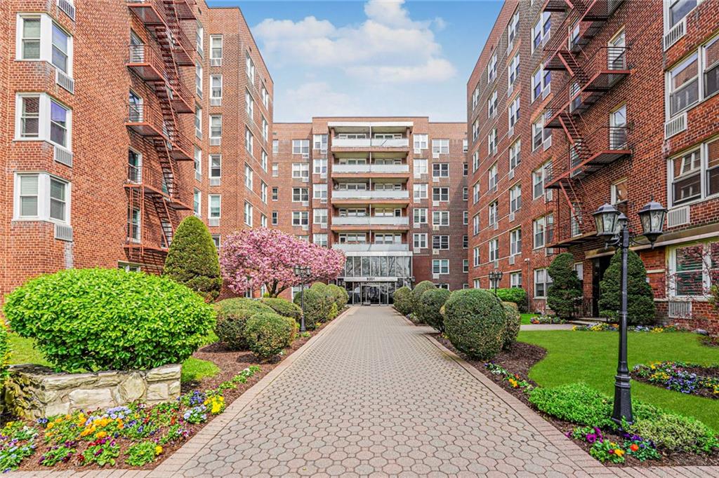 9201 Shore Road, Unit C209 Brooklyn, NY 11209 - Photo 1 of 23 a front view of a multi story residential apartment building with yard and bench
