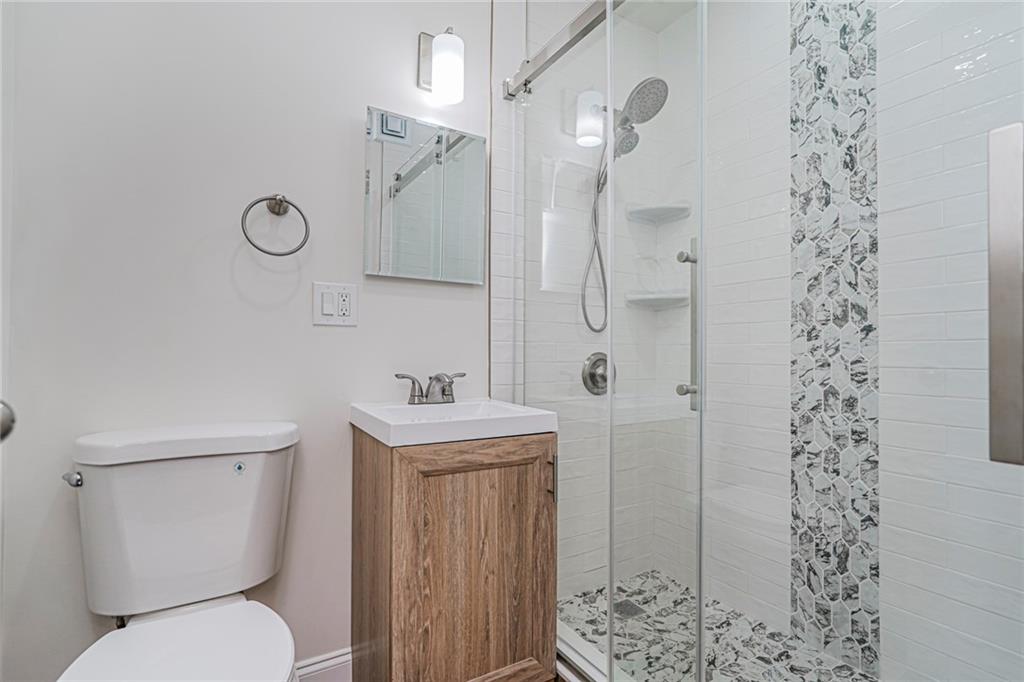 9201 Shore Road, Unit C209 Brooklyn, NY 11209 - Photo 18 of 23 a bathroom with a toilet sink vanity granite and shower