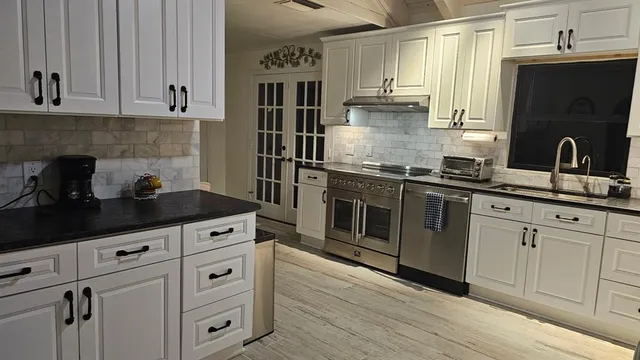 a kitchen with white cabinets and appliances