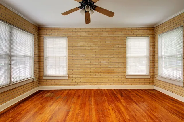 a view of an empty room with a window and wooden floor