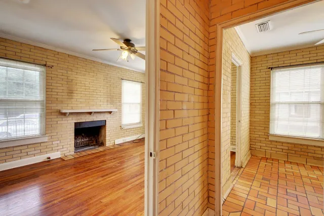 a view of an empty room with wooden floor and a fireplace