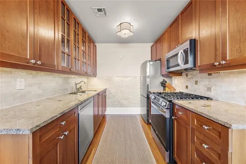 a kitchen with stainless steel appliances granite countertop wooden cabinets a stove top oven a sink and dishwasher