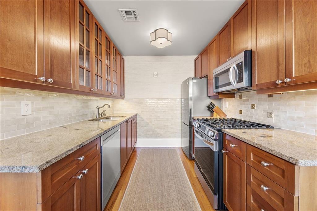 266 11th Street Northeast, Unit 203 Atlanta, GA 30309 - Photo 13 of 50 a kitchen with stainless steel appliances granite countertop wooden cabinets a stove top oven a sink and dishwasher